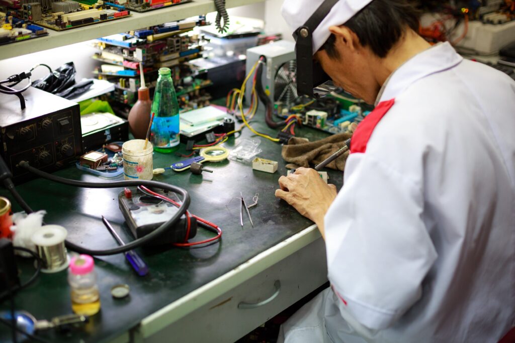 A skilled technician focuses on repairing electronic components at a busy workbench.